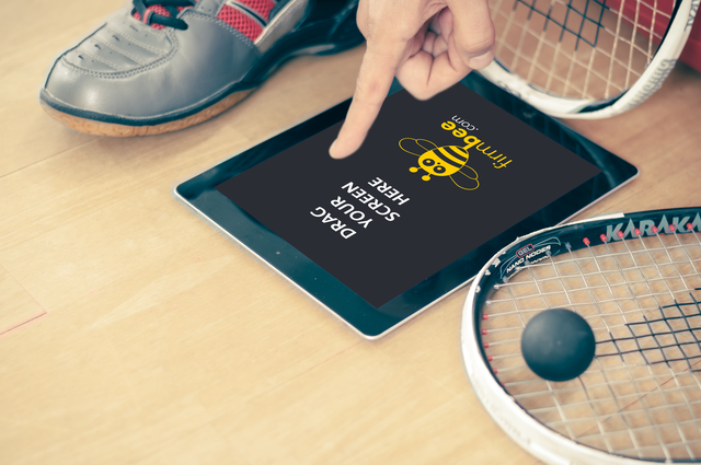 Black Apple iPad and squash racket