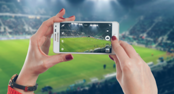 A woman is using a mobile phone at the football stadium